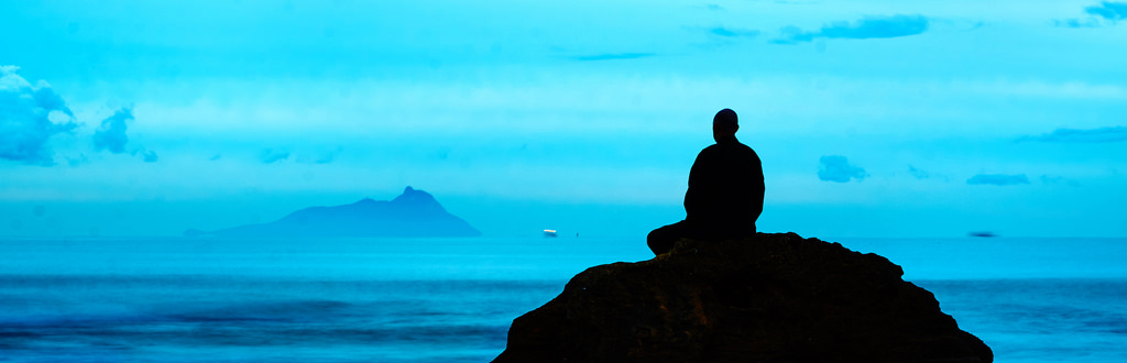 Foto con tonos azules y negros de un monge meditando